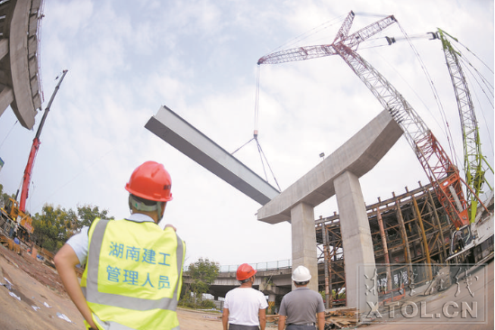 紅易-滬昆跨線橋跨滬昆高速公路主跨架梁施工現(xiàn)場，一節(jié)節(jié)鋼箱梁被吊起安裝。（記者 方陽 攝）